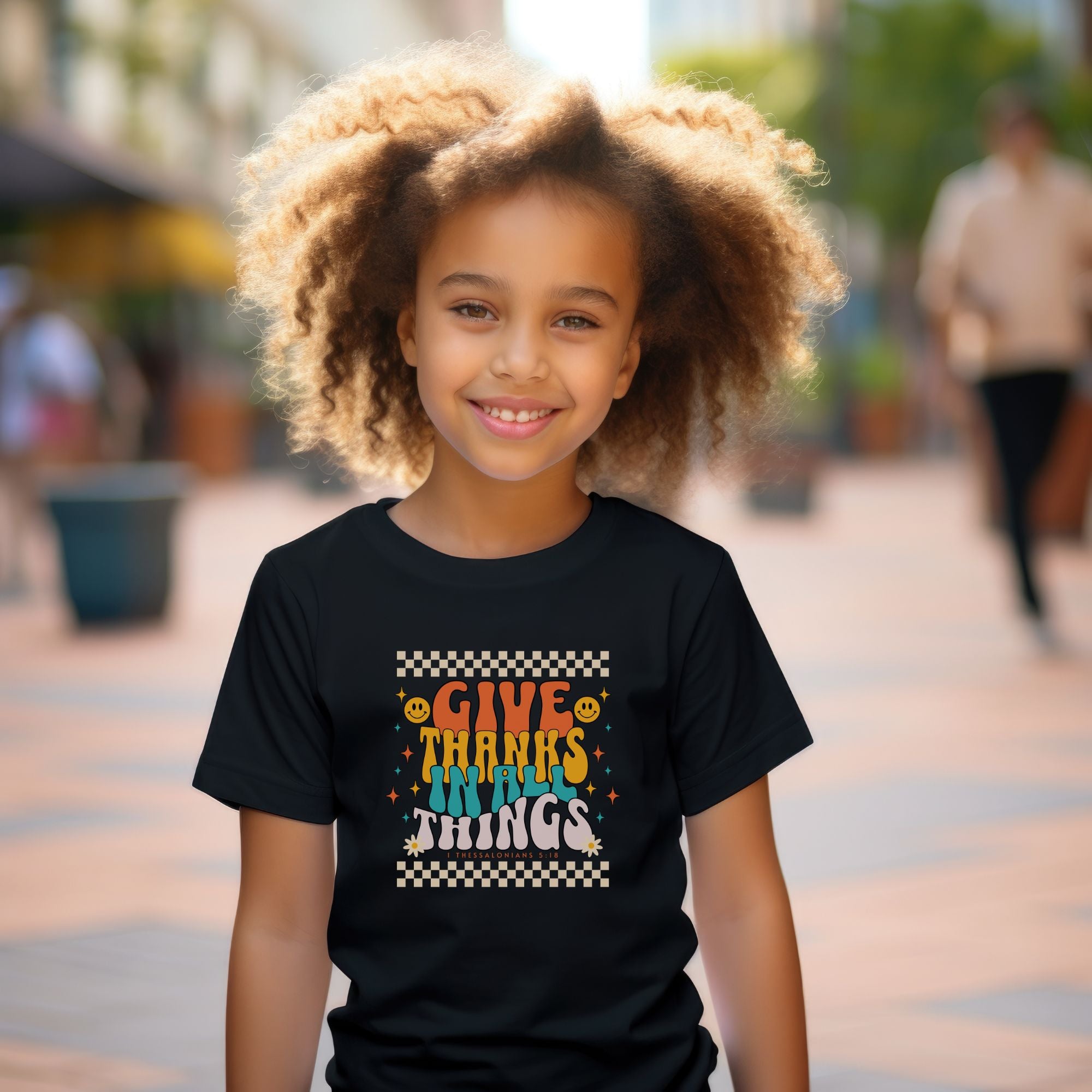 girl model wearing a black youth t-shirt with design that reads "give thanks in all things", inspired by Thessalonians 5:18